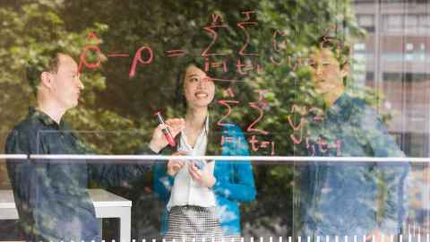 Students and a teacher doing equations on window