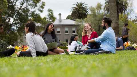 Five students sitting outside on university grounds.